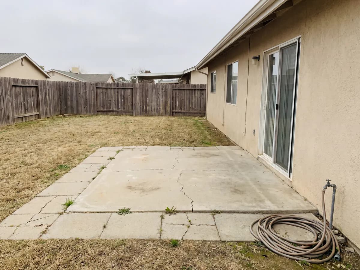 AI pergola design before and after: a bare patio photo redesigned with a pergola over the seating area.