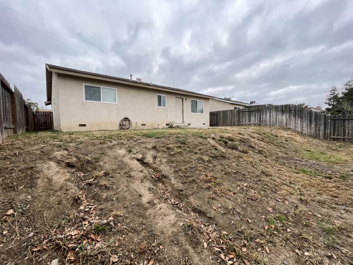 AI retaining wall design before and after: a sloped yard photo redesigned with a terraced block wall.