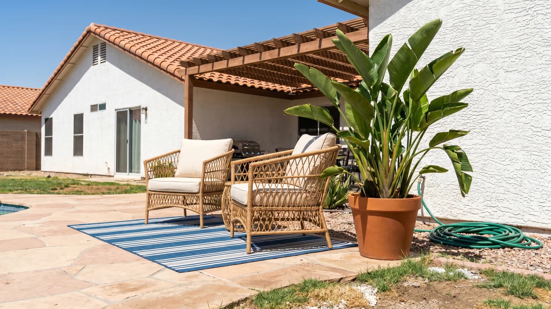 Outdoor rug and large planters styled on a small pool deck beside a Spanish stucco house in Arizona
