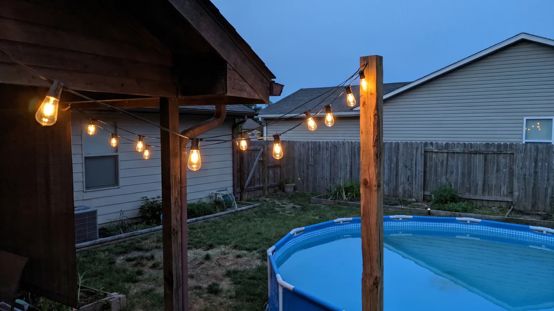 Solar string lights glowing over an above ground pool area at dusk