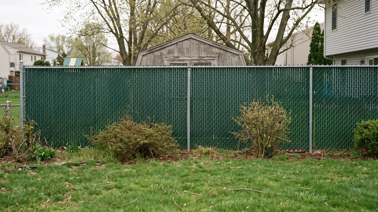 Six-foot chain link fence filled with dark green vinyl privacy slats