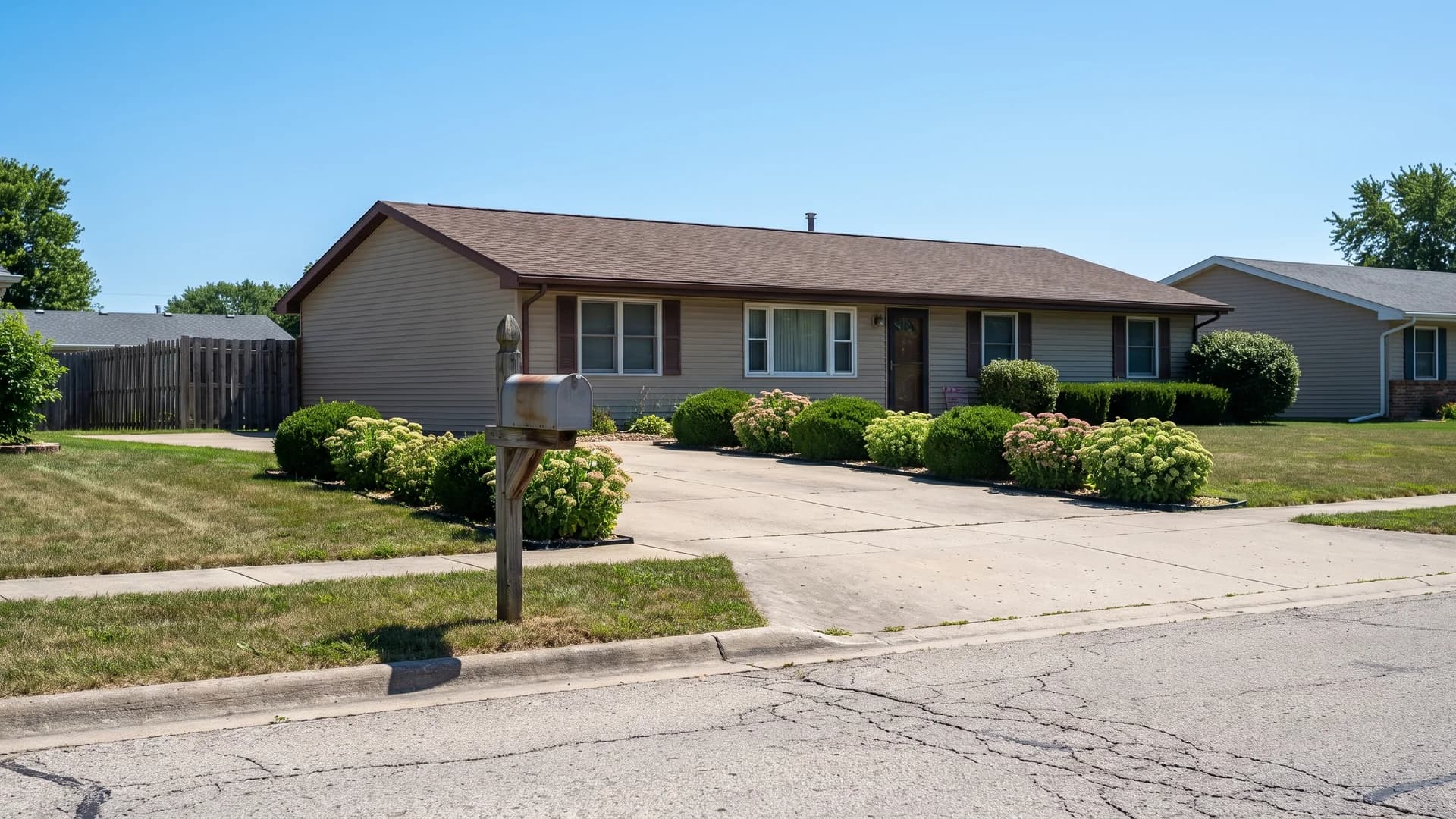 Low mounded shrubs under two feet tall at the street end of a concrete driveway