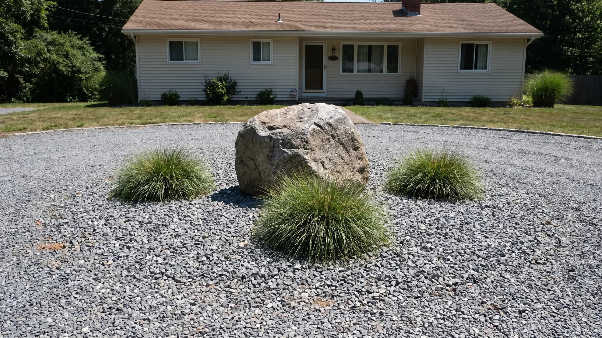 Circular driveway island landscaped with rock, one boulder, and low plants