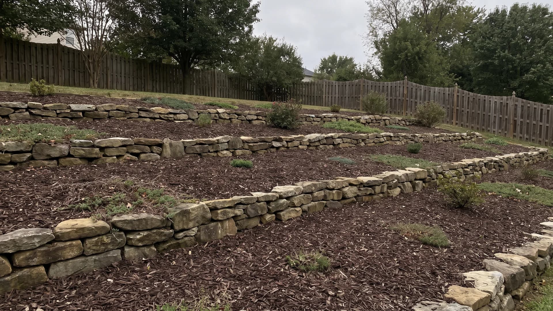 Fieldstone rows running across a mulched slope holding the mulch in place