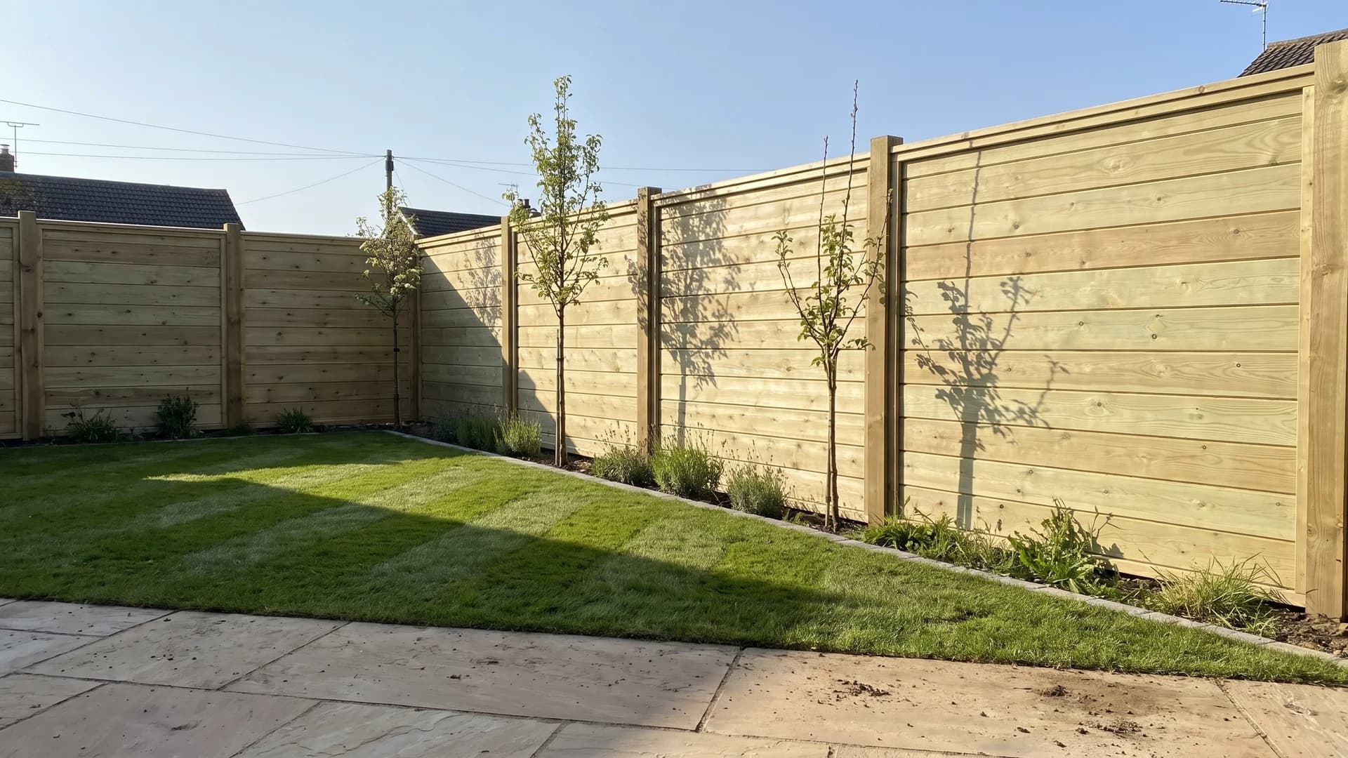 Solid tongue-and-groove acoustic timber fence panels behind a lavender-edged lawn
