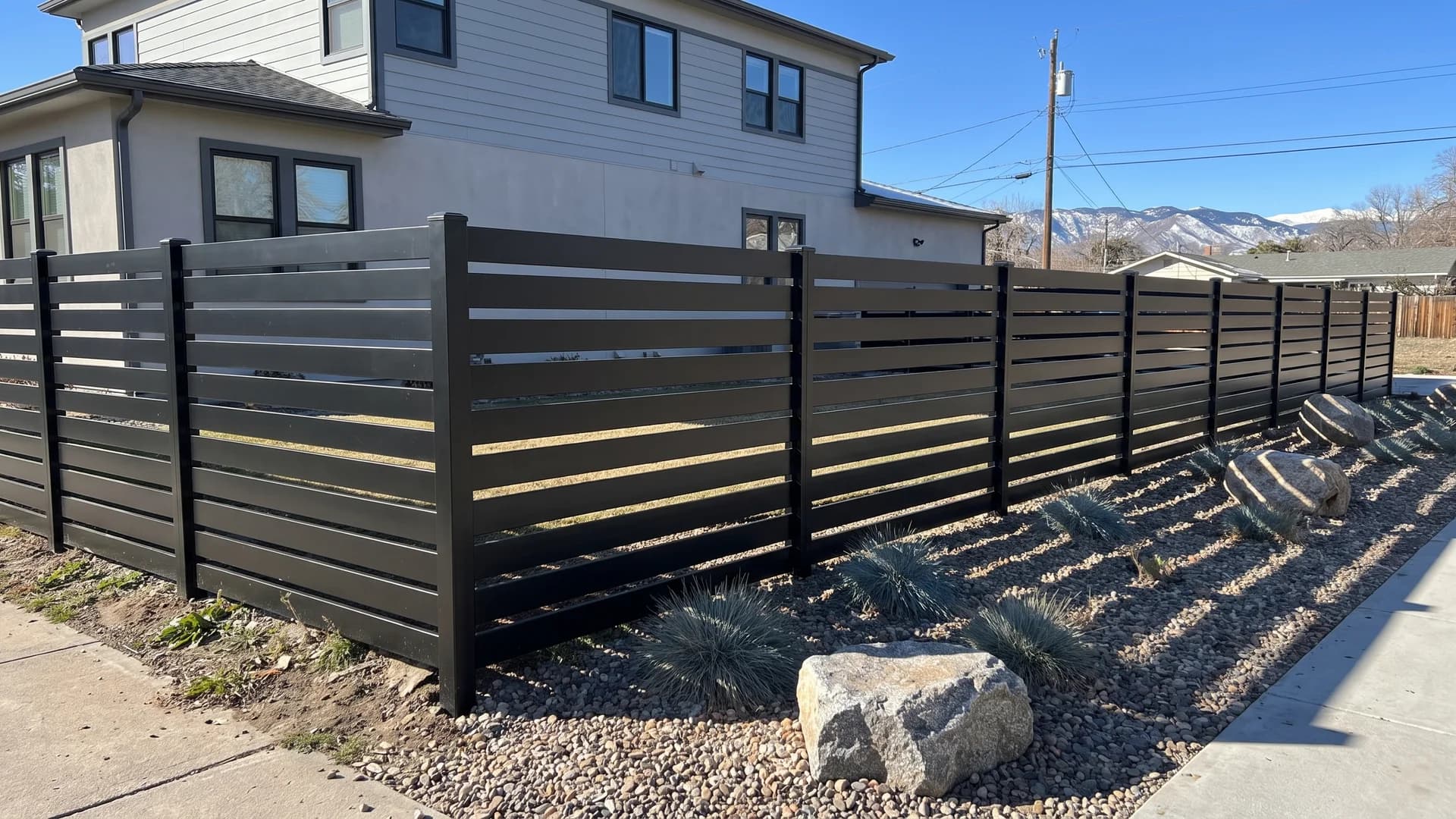 Matte black aluminium horizontal slat fence with even gaps around a xeriscaped front garden