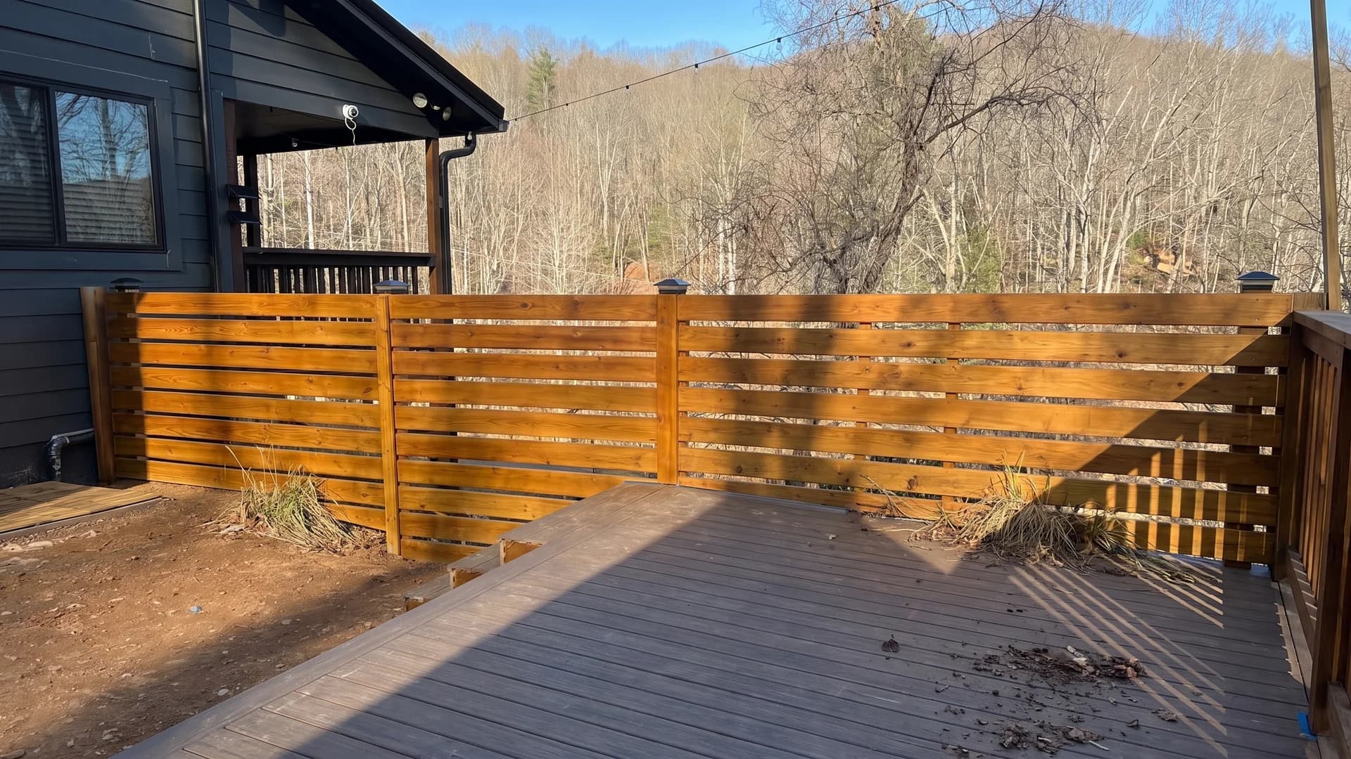 Honey cedar fence with even gaps and solar post caps beside a mountain house deck
