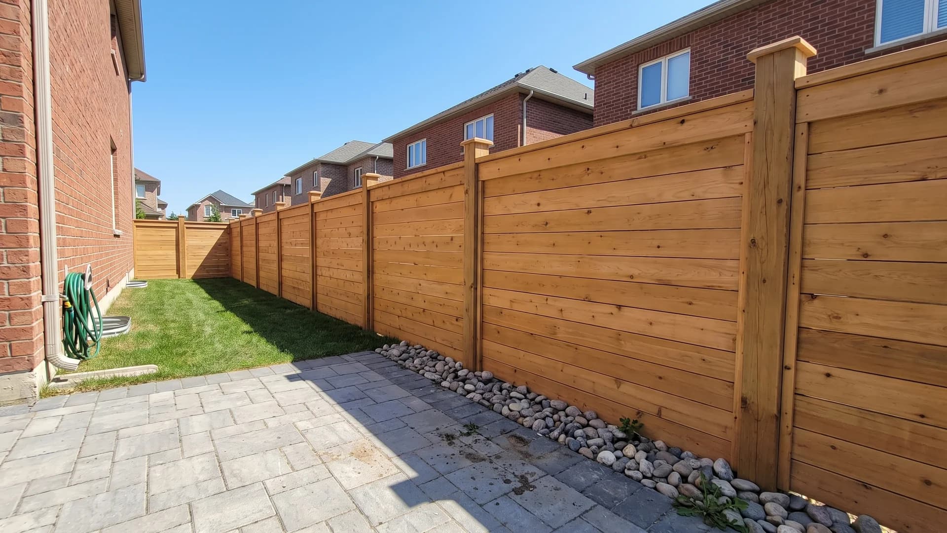 Honey cedar fence with a flat capped top rail beside a paver walkway