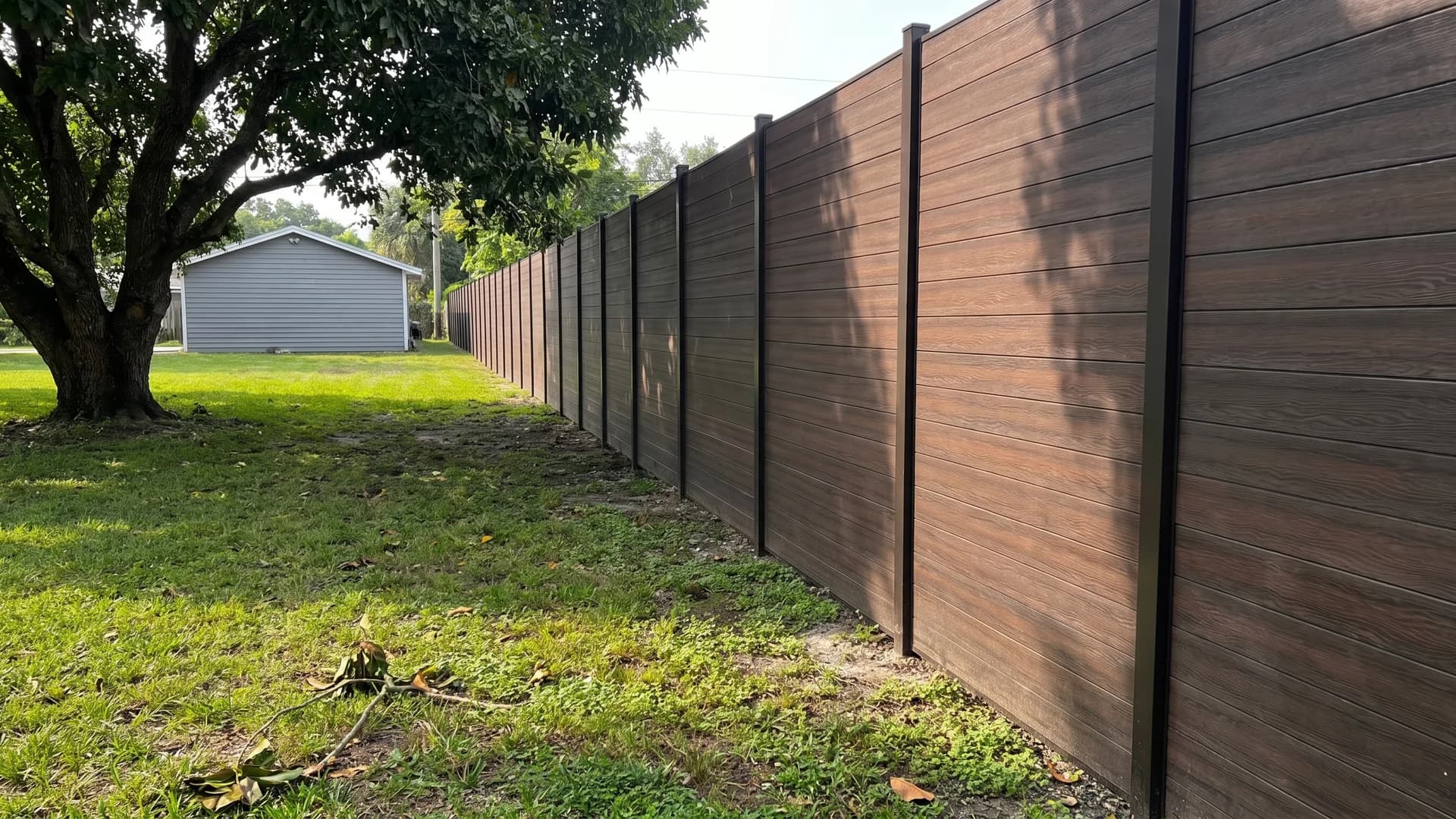 Near-black espresso composite fence boards along a shaded lawn