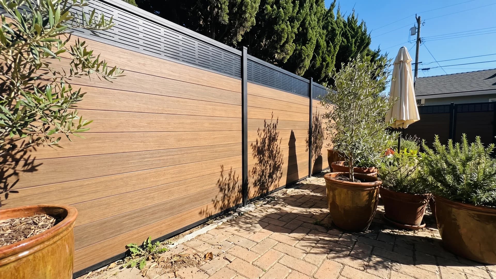 Caramel composite horizontal boards topped by a black laser-cut metal panel in a courtyard