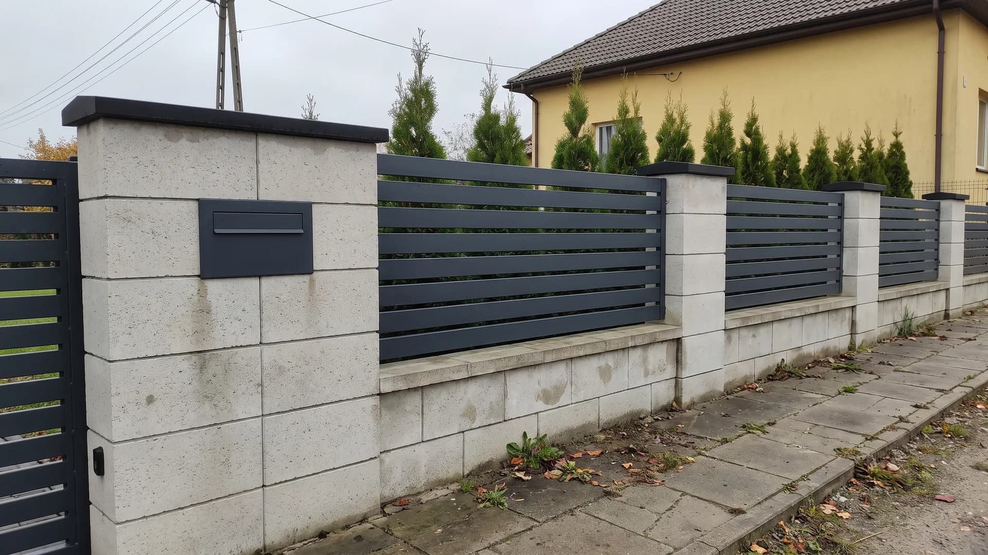 Anthracite metal horizontal panels set between split-face concrete block pillars