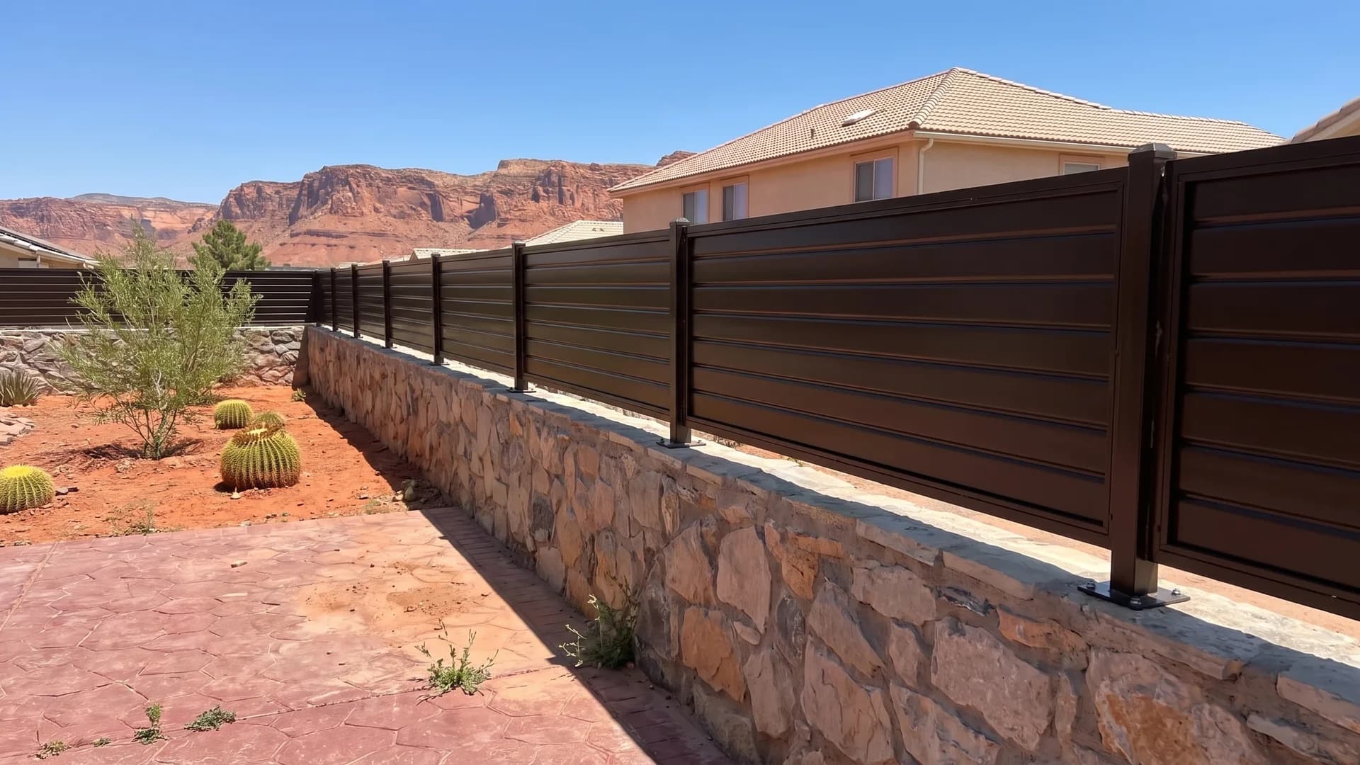Bronze horizontal metal fence panels bolted above a stacked stone retaining wall