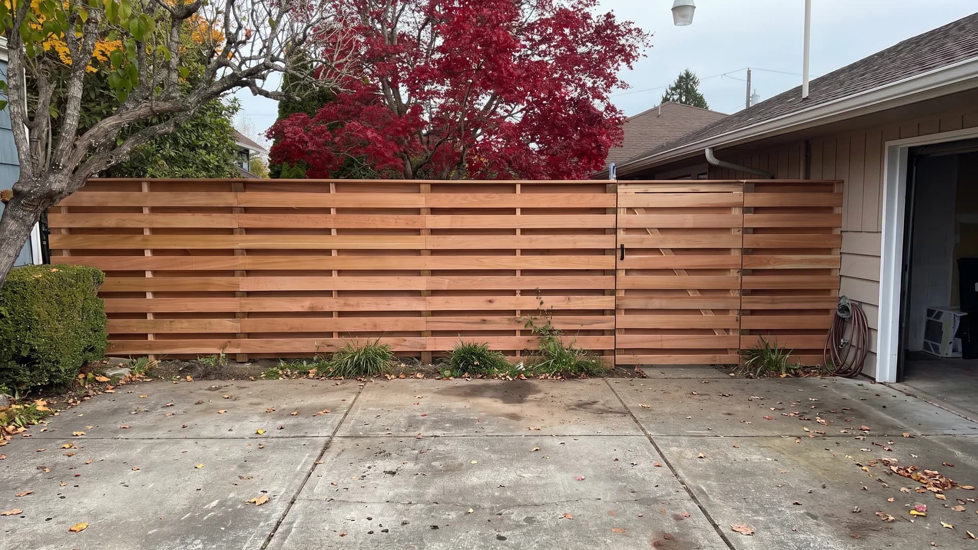 Red cedar shadowbox fence with alternating boards and a matching gate on a driveway