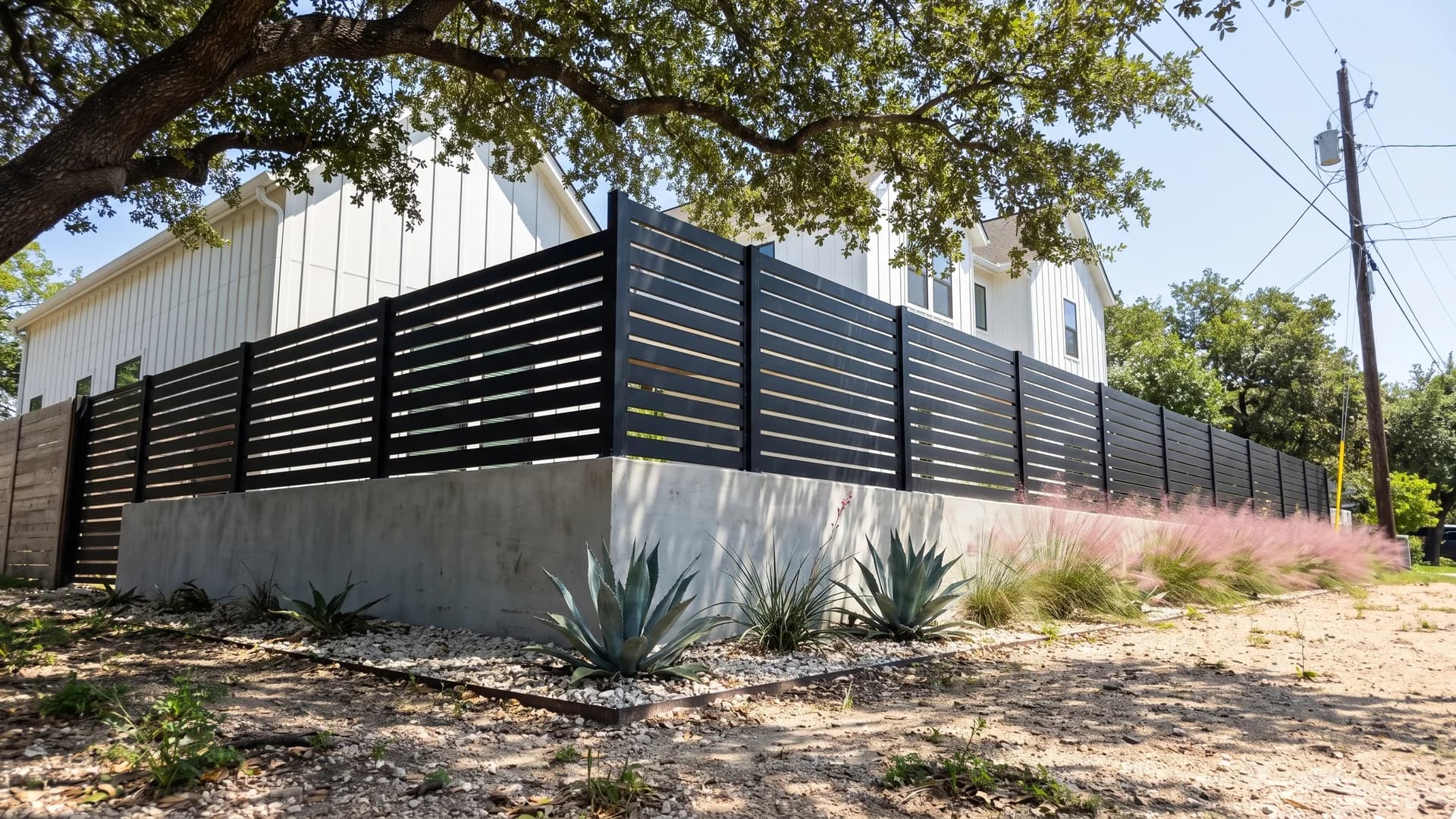 Black horizontal metal slats mounted on a board-formed concrete knee wall in a front garden