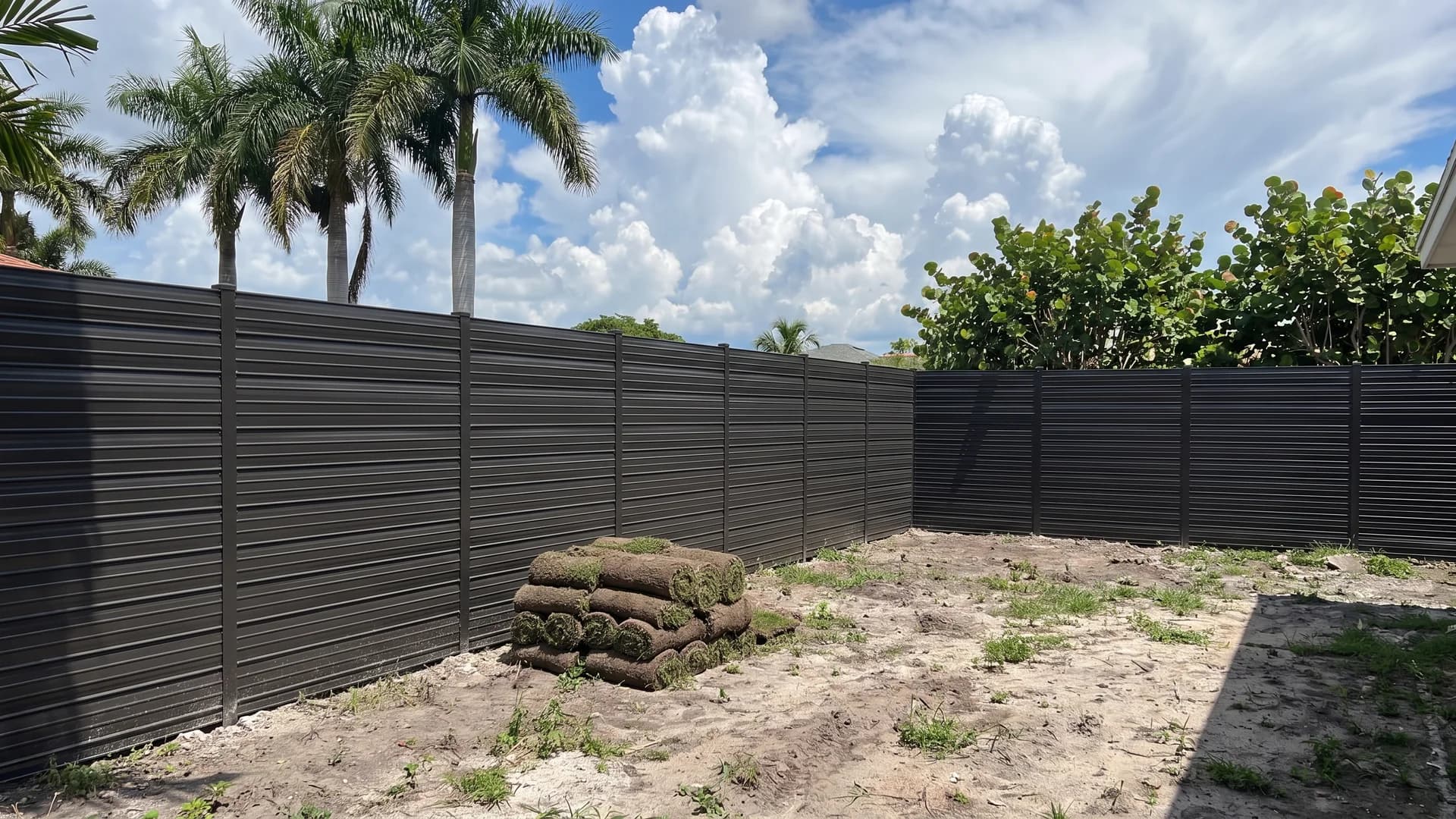 Bronze aluminium fence with tightly stacked horizontal louver blades enclosing a side garden