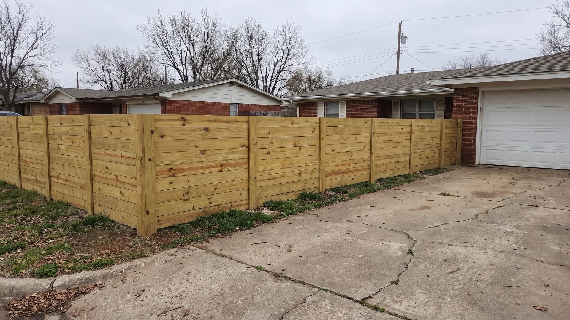 Horizontal fence ideas shown with bare pressure-treated pine boards along a flat front yard