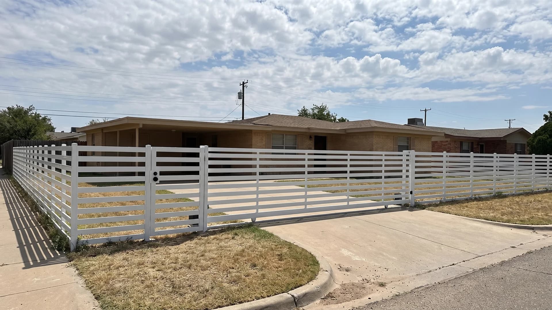 White aluminium horizontal slat fence with a matching sliding driveway gate on a corner lot
