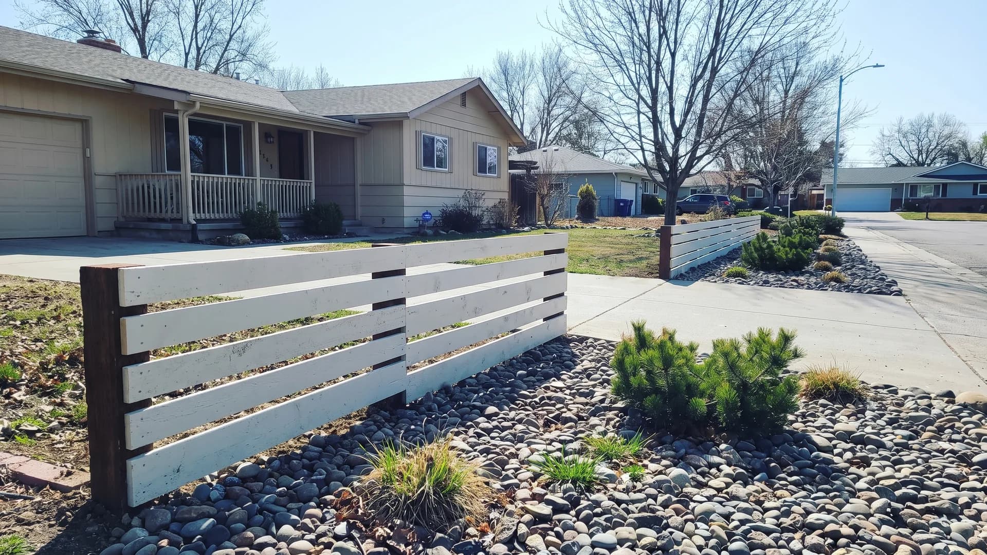 Chalky white horizontal boards with wide gaps on dark timber posts in a front yard