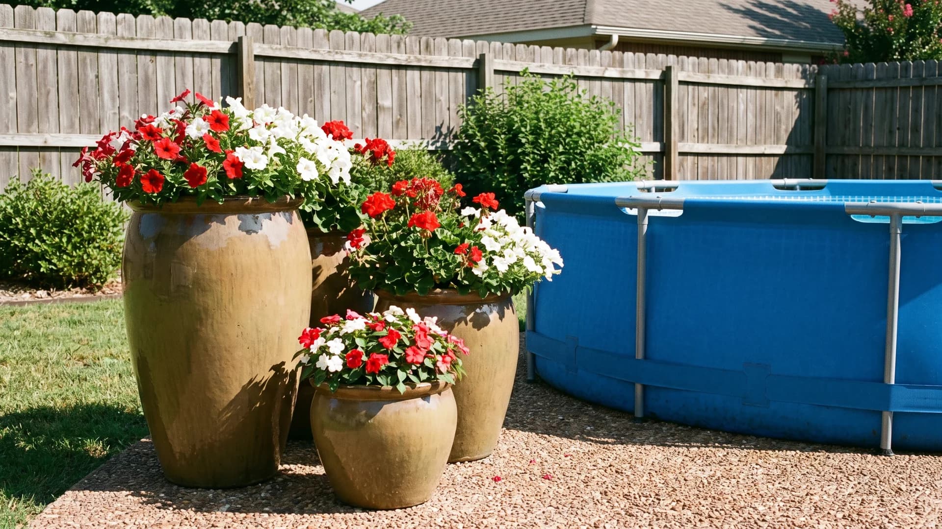 Large planters with flowers arranged on gravel beside an above ground pool