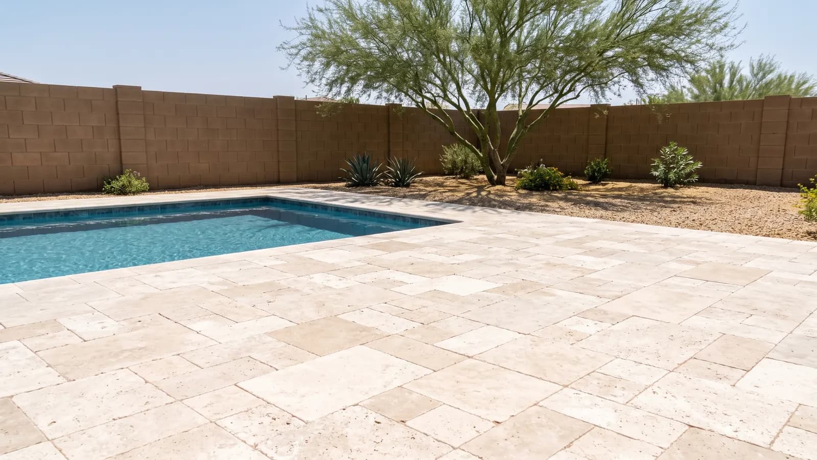 Ivory tumbled travertine pavers in a French pattern around a rectangular pool in an Arizona backyard