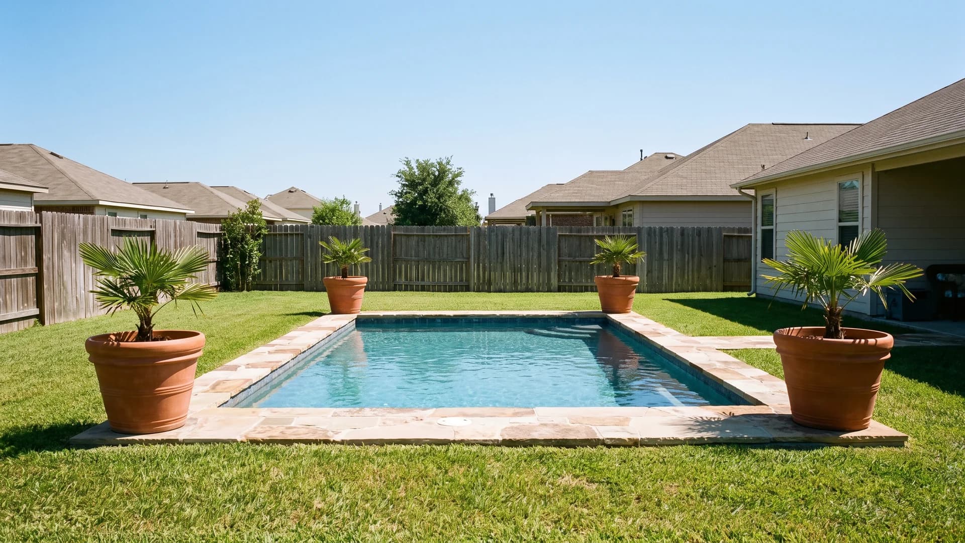 Four large pots with tropical plants marking the corners of a rectangular pool