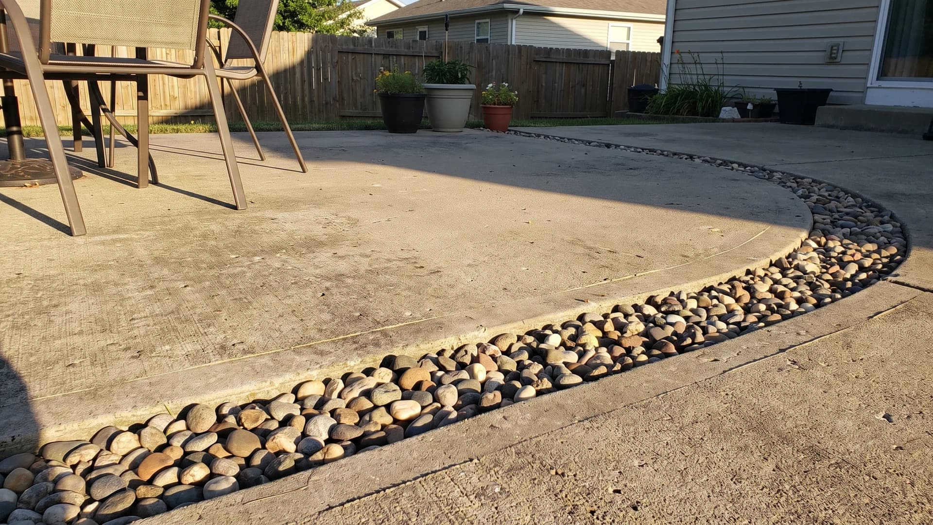 Concrete patio with a band of small river pebbles set into the surface